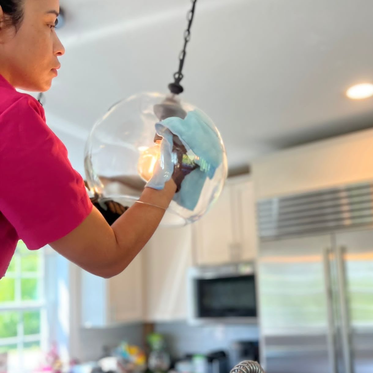 Residential glass cleaning service featuring a technician removing smudges and buildup from large interior windows and frames.