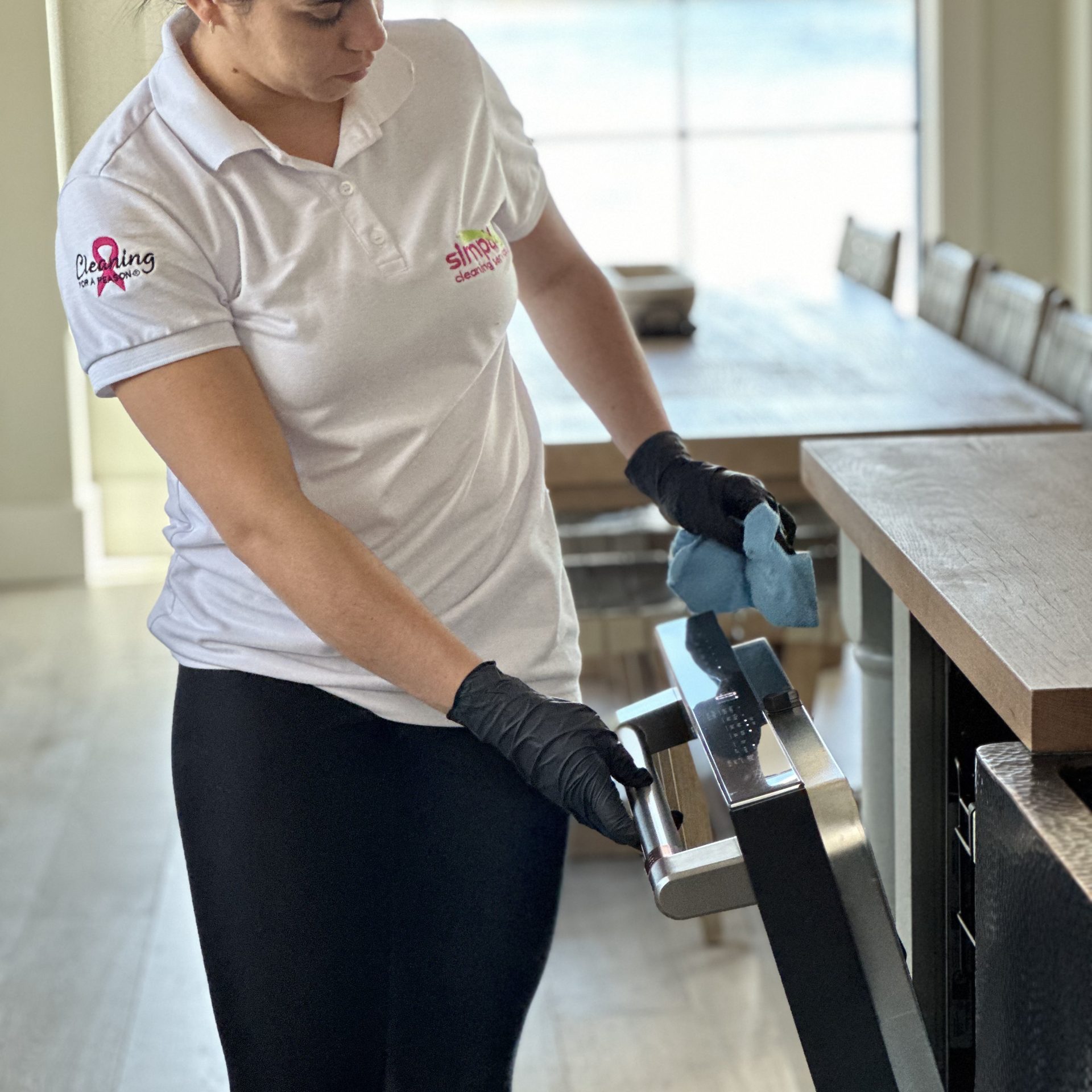 Detailed kitchen appliance cleaning service featuring a technician in black gloves wiping down a dishwasher for a move-in ready home.