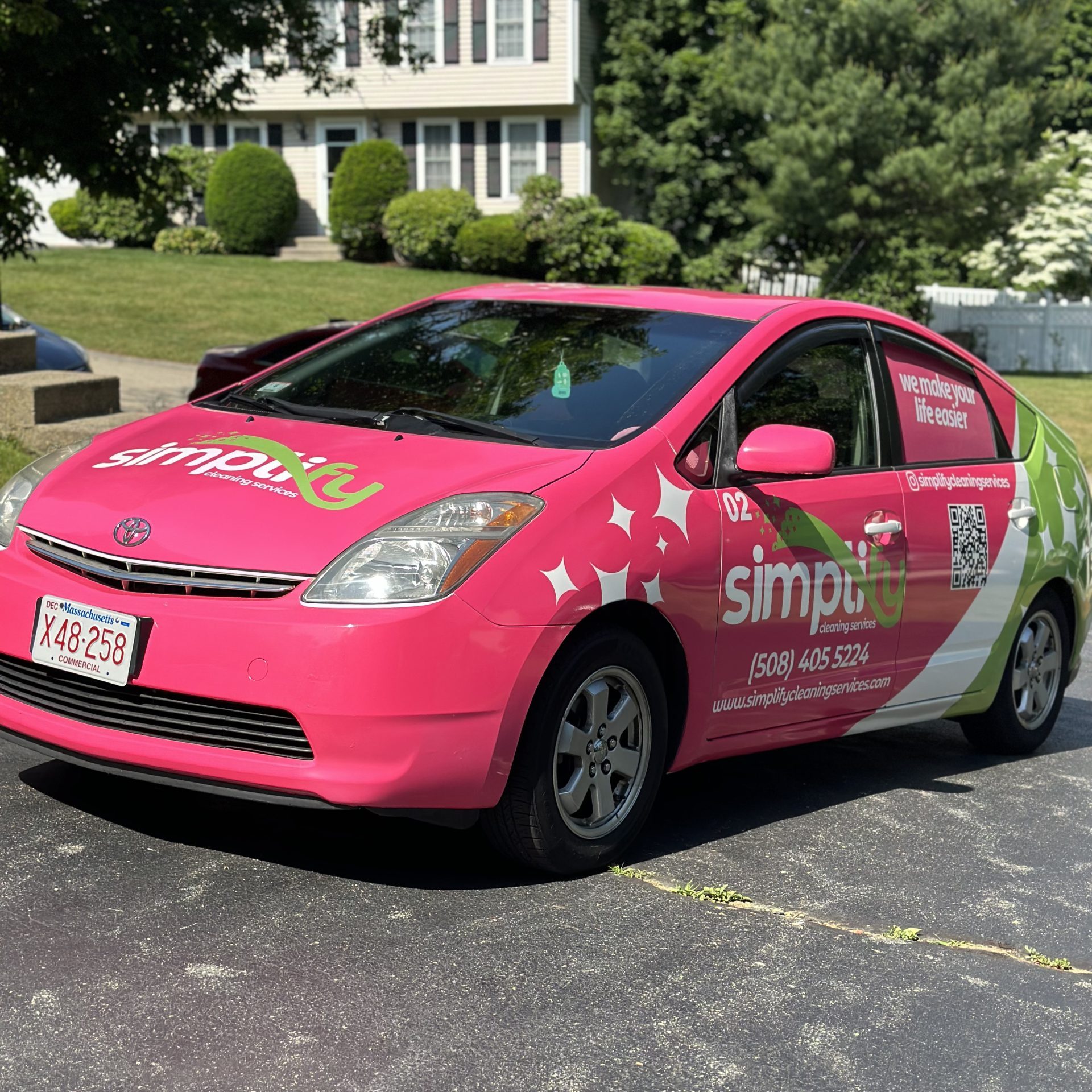 A bright pink Simplify Cleaning Services branded vehicle parked in a residential driveway, delivering professionals to an expert cleaning service.