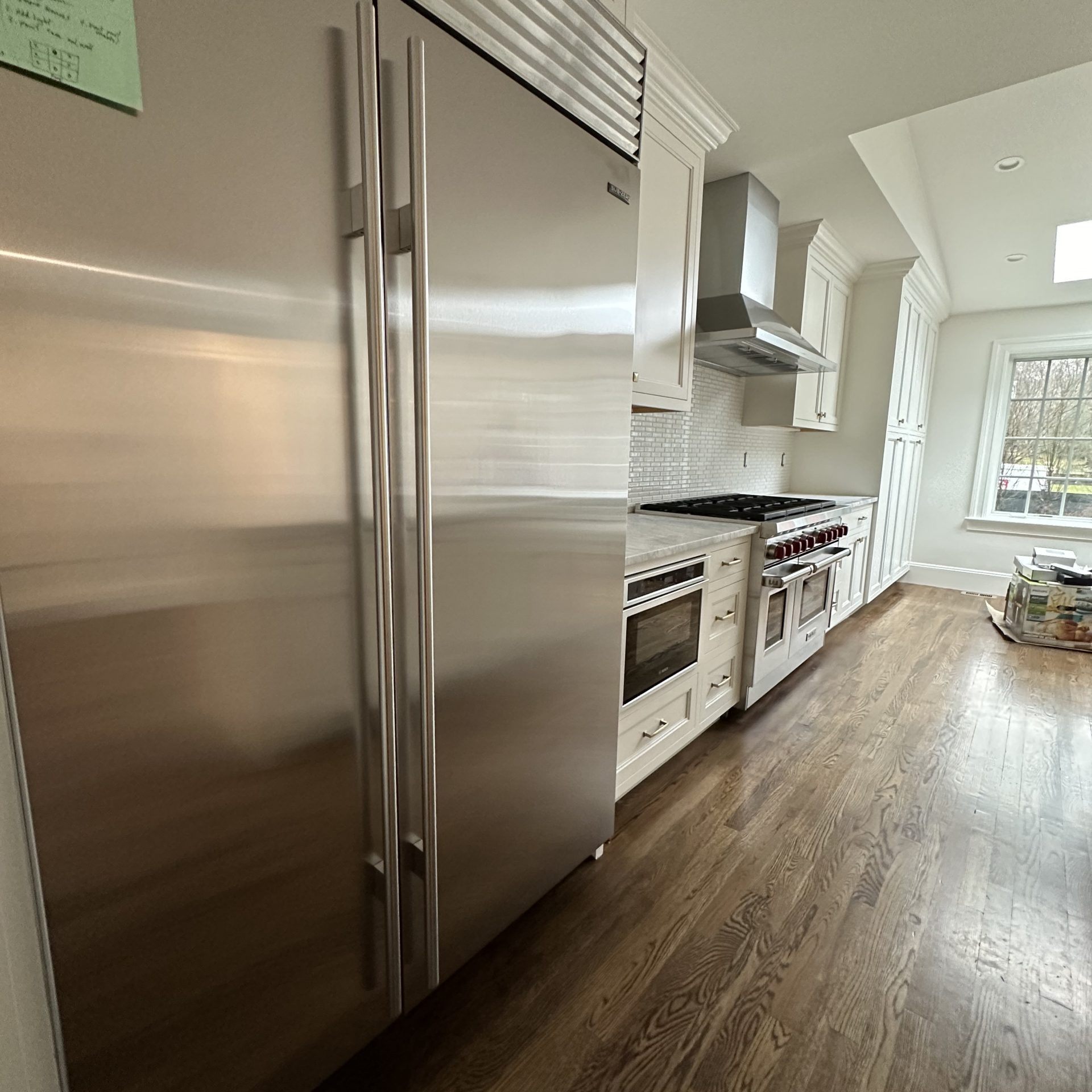 A spotless, move-in ready kitchen featuring gleaming stainless steel appliances, white cabinetry, and polished hardwood floors after a professional deep clean by Simplify Cleaning Services.